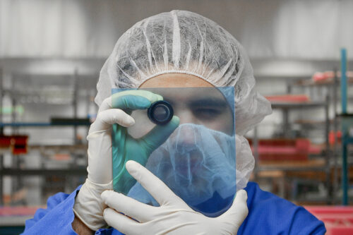 Photo of technician closely examining a display overlay with an eye loupe